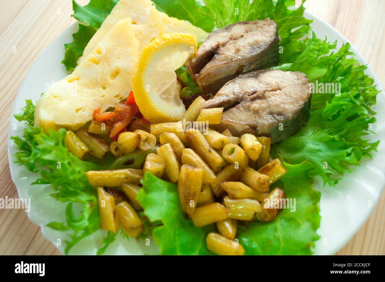 Gebratener Fisch mit Gemüse garnieren mit grünem Salat auf A Holzhintergrund Stockfoto
