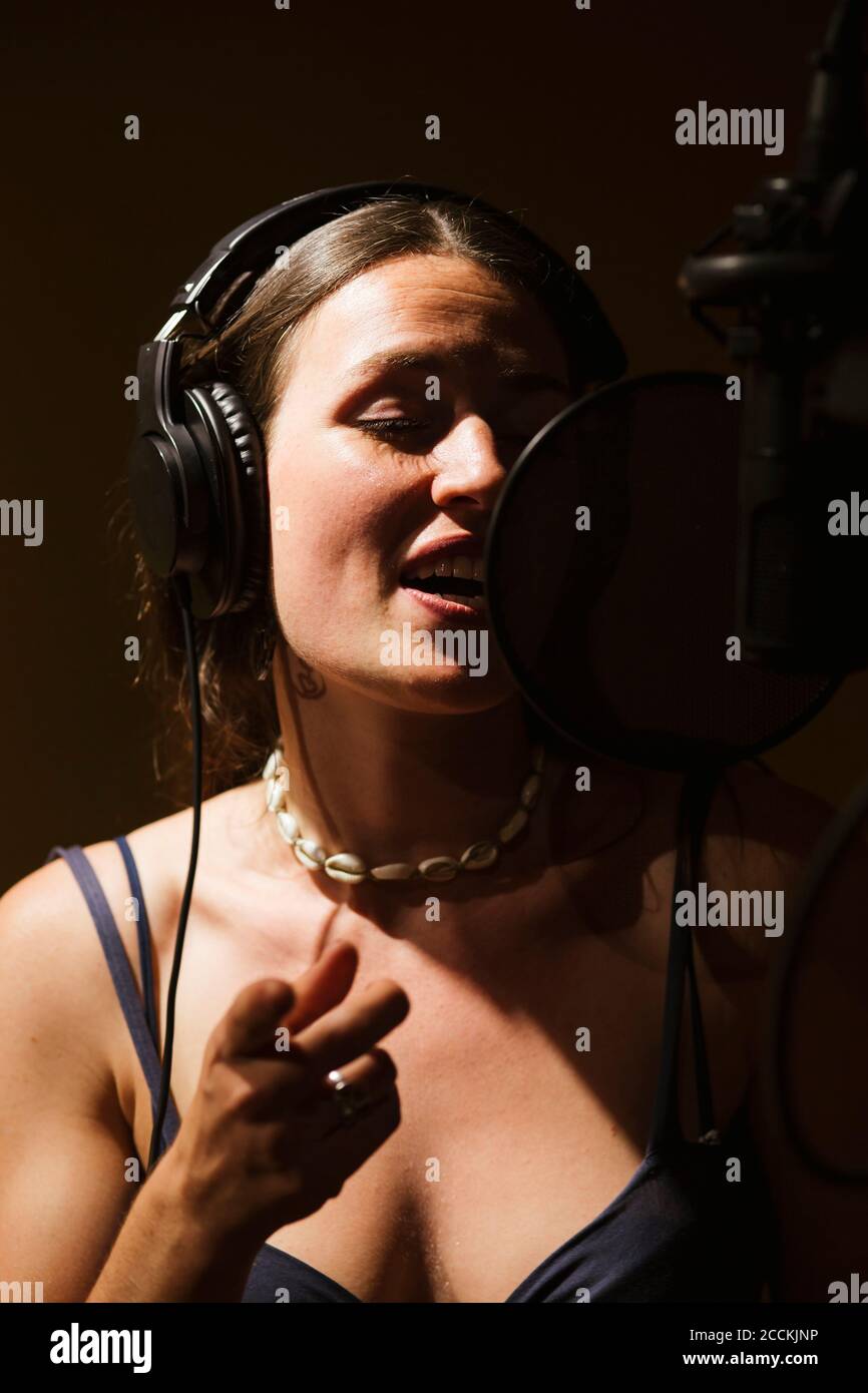Sänger mit Kopfhörern am Mikrofon im Aufnahmestudio Stockfoto