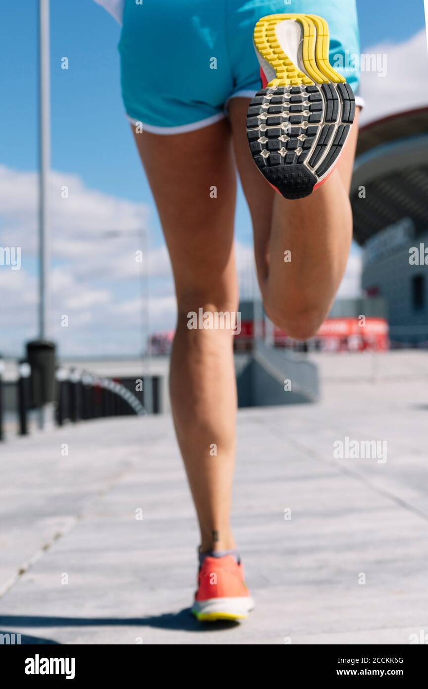 Beine einer mittleren erwachsenen Frau, die auf dem Bürgersteig in der Stadt läuft An sonnigen Tagen Stockfoto