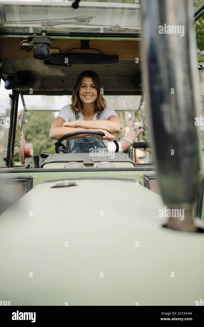 Porträt einer selbstbewussten jungen Frau in einem Traktor Stockfoto