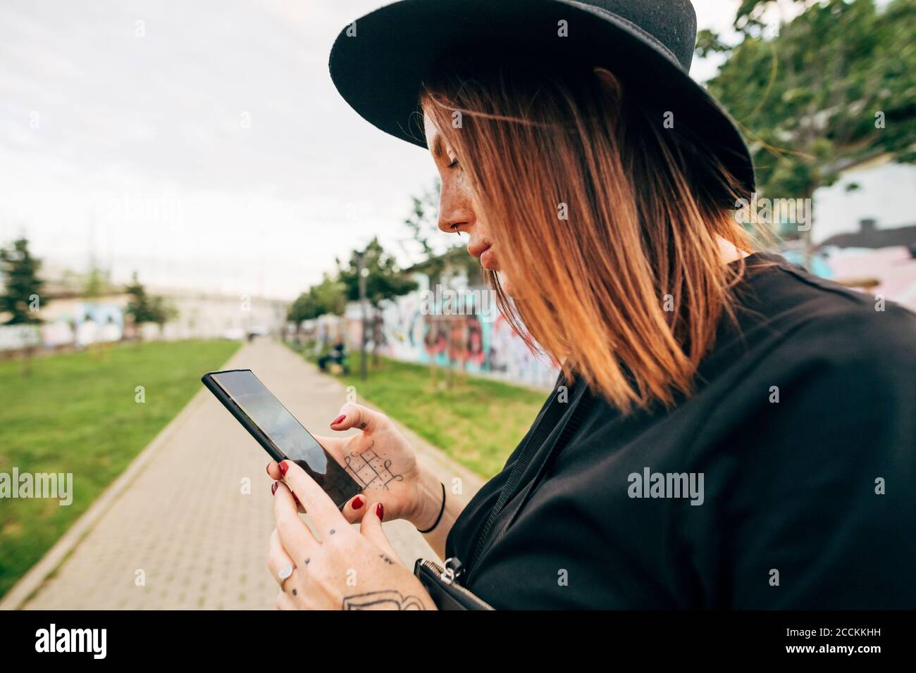 Nahaufnahme einer jungen Frau mit Hut und Smartphone parken Stockfoto
