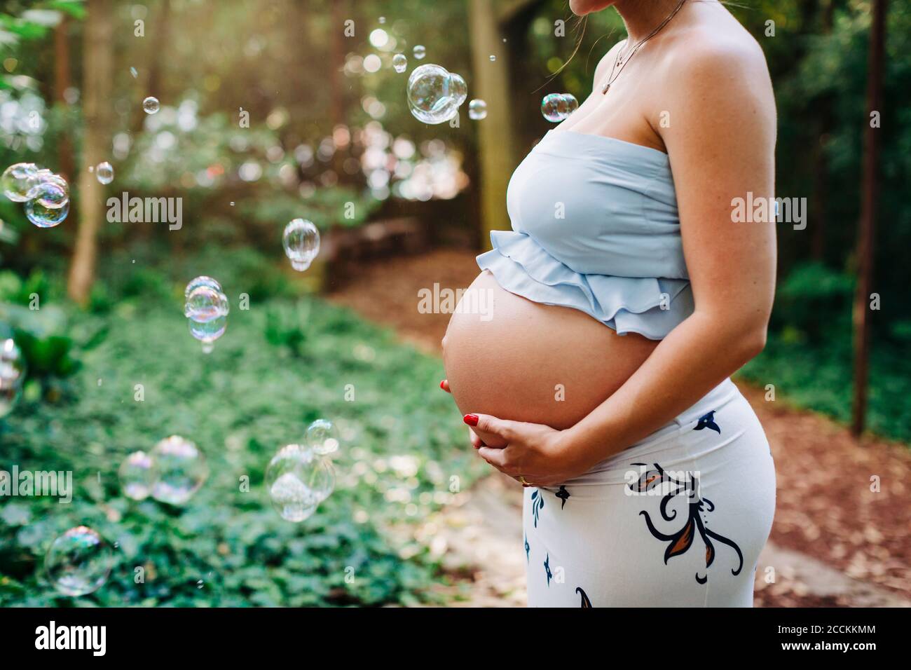 Schwangere Frau mit den Händen auf dem Bauch stehen von Blasen an parken Stockfoto