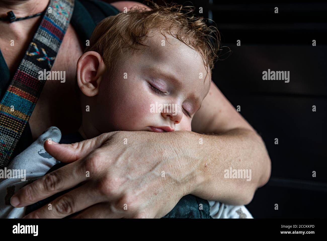 Mutter umarmt schlafenden Baby Sohn Stockfoto