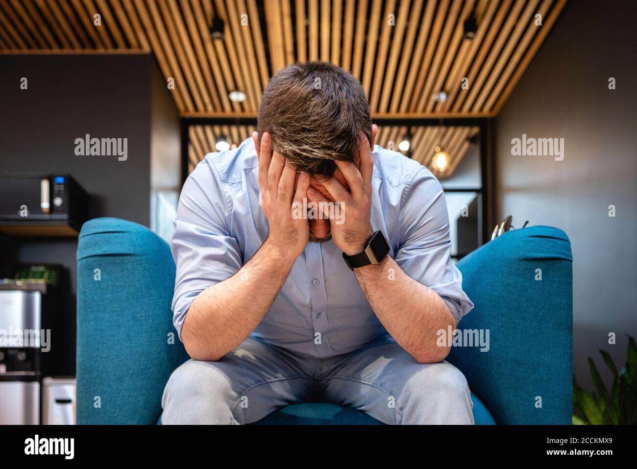 Besorgter Geschäftsmann mit Kopf in den Händen auf dem Sessel sitzen Bürocafeteria Stockfoto