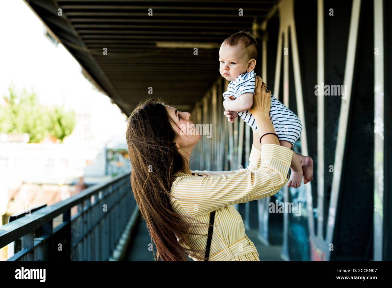 Mutter hebt ihren kleinen Jungen auf einer Brücke Stockfoto
