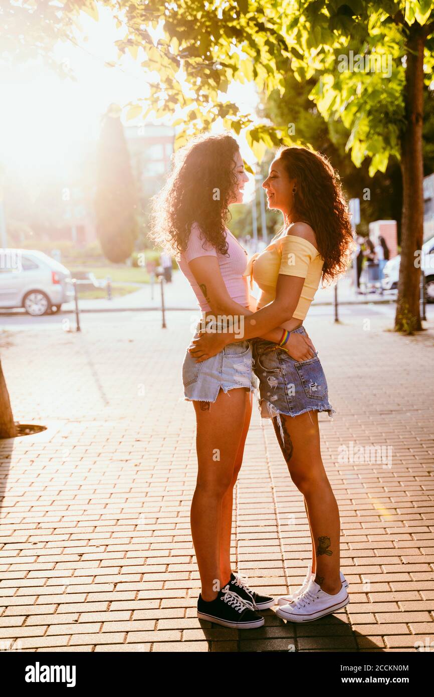 Lesben, die einander angucken, während sie auf dem Fußweg stehen Stadt an sonnigen Tagen Stockfoto