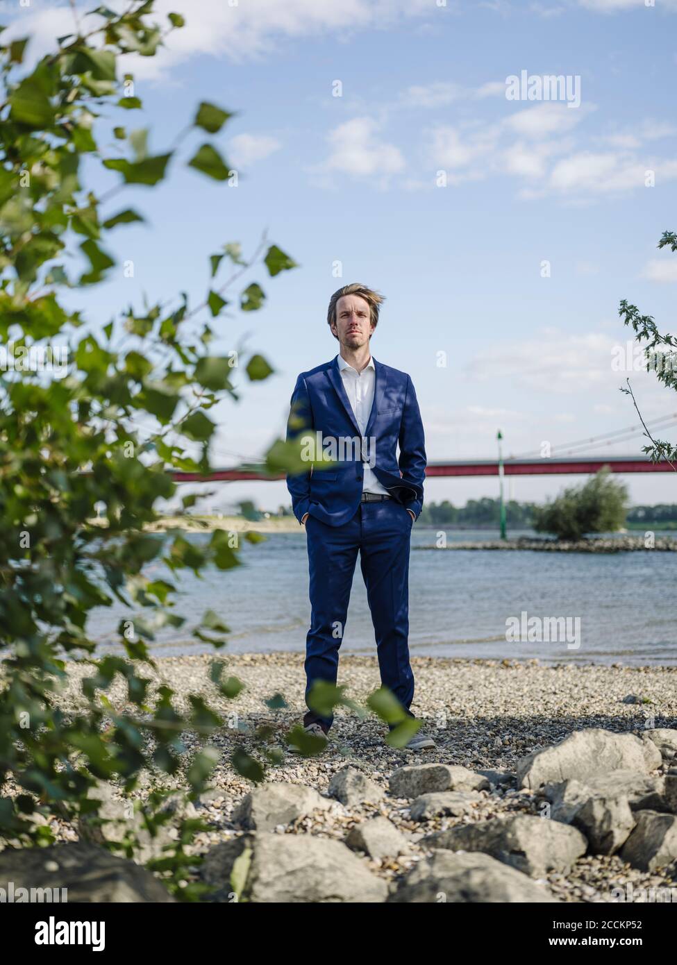 Seriöse Geschäftsmann steht gegen Rhein und Himmel Stockfoto