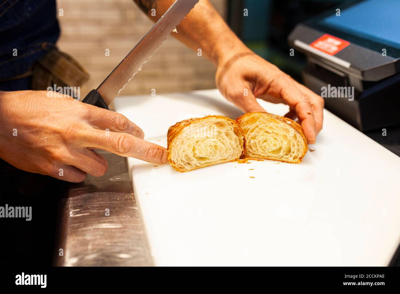 Bäcker, der Brot über der Küchentheke in der Bäckerei schneidet Stockfoto