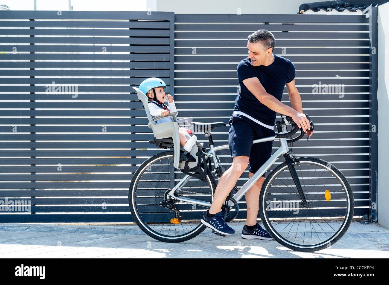 Vater mit Sohn sitzt in der Sicherheit Sitz des Fahrrads Stockfoto