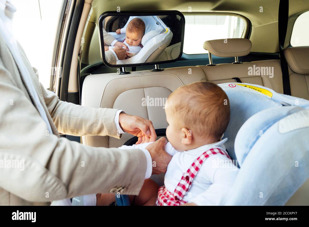 Vater Befestigung Baby Junge sitzen auf Kindersitz in einem Auto Stockfoto