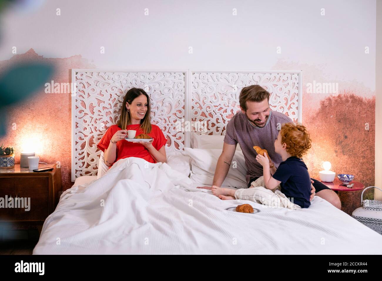 Glückliche Eltern mit Sohn beim Frühstück auf dem Bett zu Hause Stockfoto