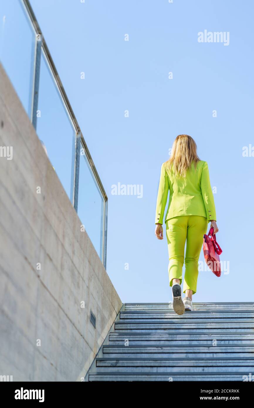 Geschäftsfrau bewegt sich auf Stufen gegen klaren Himmel Stockfoto