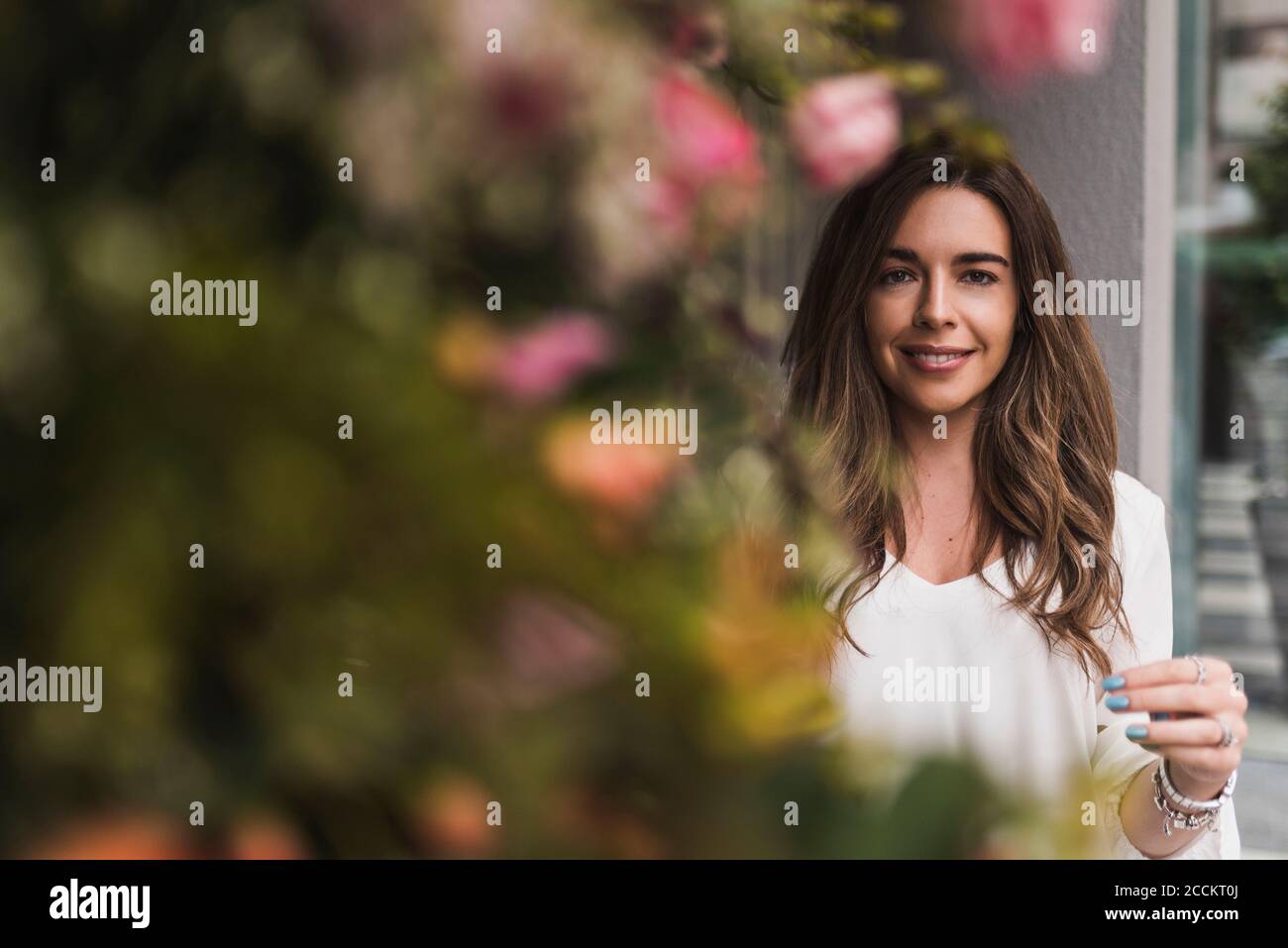 Selbstbewusste Frau, die vor dem Laden neben den Pflanzen steht Stockfoto