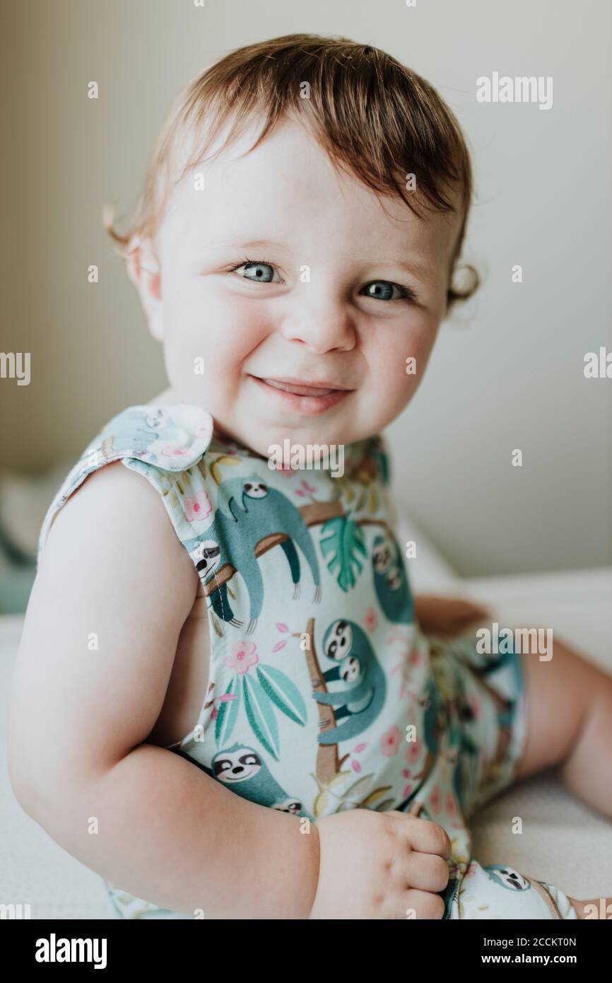 Close-up von niedlichen lächelnd Baby Mädchen auf dem Tisch sitzen bei Zu Hause Stockfoto