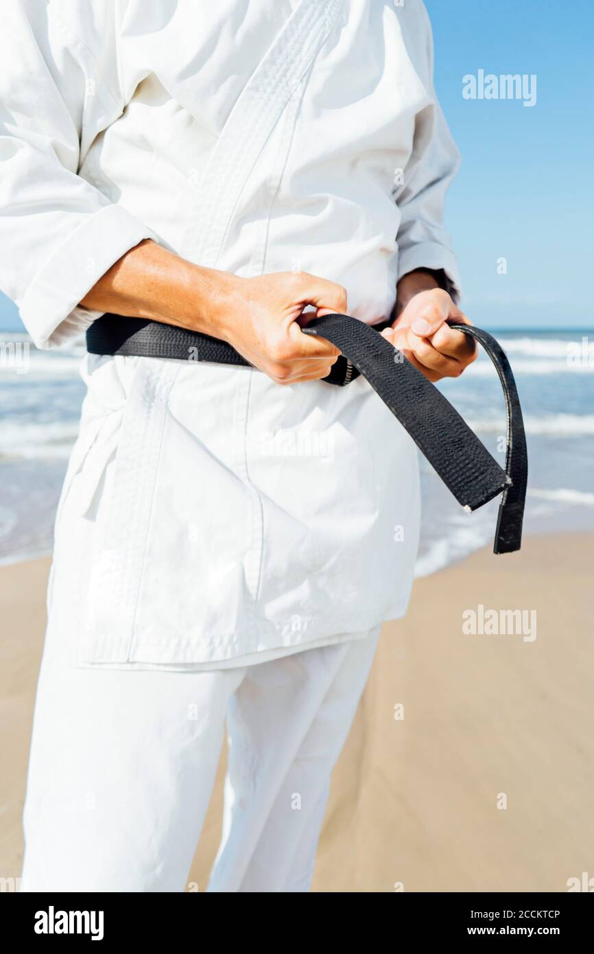 Nahaufnahme eines reifen Mannes, der beim Stehen schwarzen Gürtel bindet Strand Stockfoto