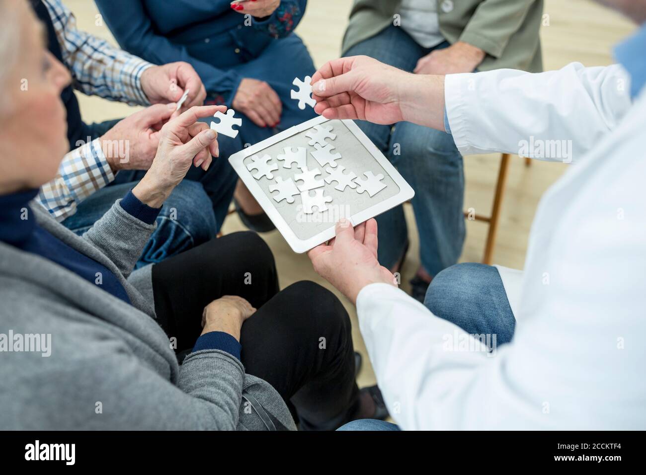 Doktor spielen Puzzle mit Gruppe von Senioren im Ruhestand Zu Hause Stockfoto
