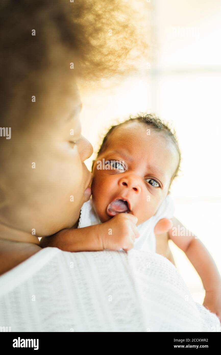 Nahaufnahme der Mutter küssen Baby Tochter, während sie zu tragen Zu Hause Stockfoto