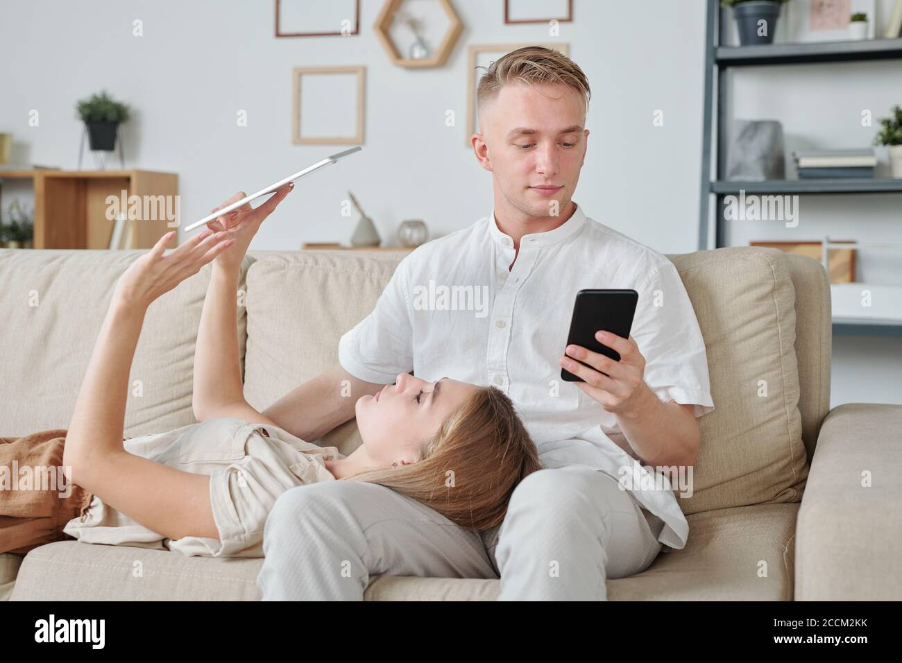 Junge Frau mit digitalen Tablet, während sie den Kopf auf Knie des Mannes Stockfoto