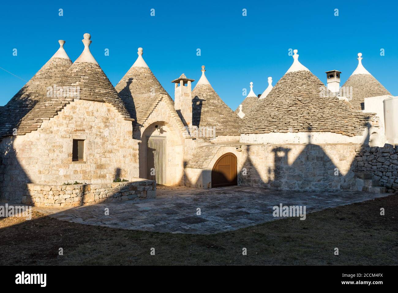 Gruppe von Trulli, traditionelle alte Häuser und alte Steinmauer in Apulien, Italien Stockfoto