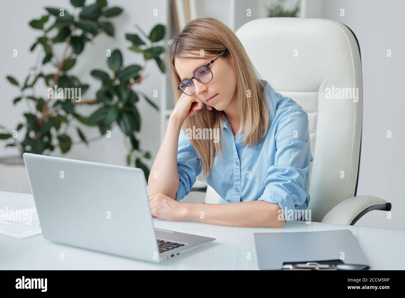 Junge müde Geschäftsfrau mit blonden Haaren Blick unglücklich auf Laptop Anzeigen Stockfoto