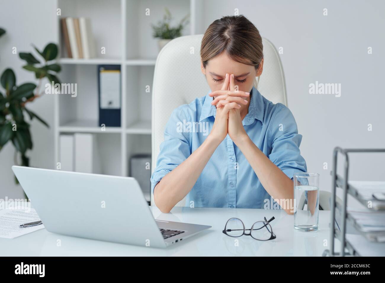 Eine moderne Geschäftsfrau, die beim Brainstorming die Hände im Gesicht hält Stockfoto