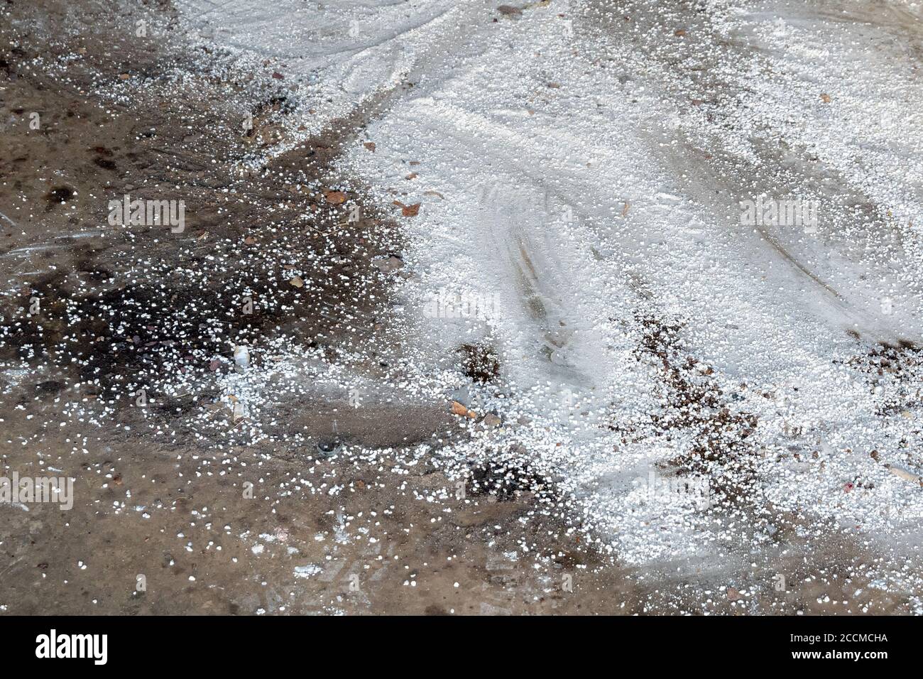 Weißes saugfähiges Kehrpulver auf einem Garagenboden. Auf der linken Seite ist ein bisschen Öl zu sehen. Stockfoto
