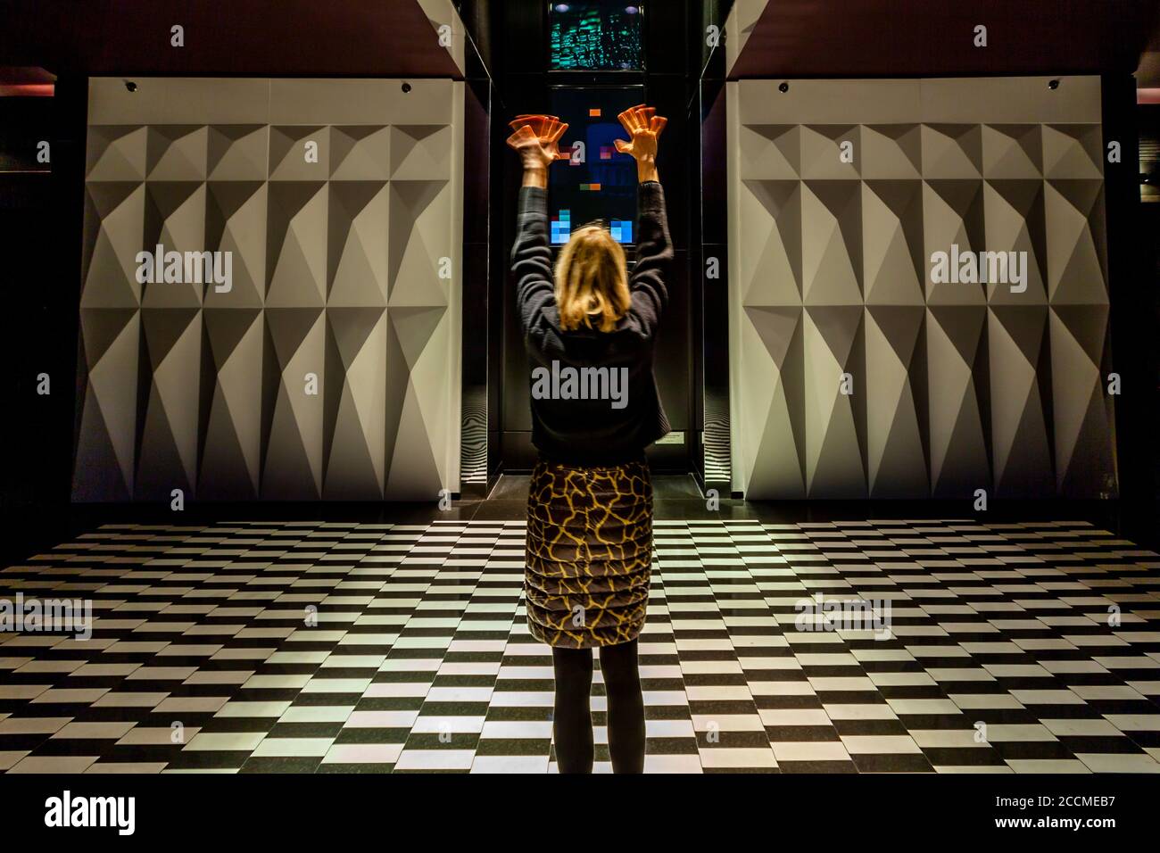 Journalistin Angela Berg hebt ihre Hände vor dem Bildschirm der Installation "Blow Up" von Rafael Lozano-Hemmer im Hotel Blow Up Hall 5050 in Posen, Polen – hier wird jeder Gast Teil eines Kunstexperiments. Mehr als 3.000 virtuelle Kameras lösen sie in Pixel auf. Stockfoto