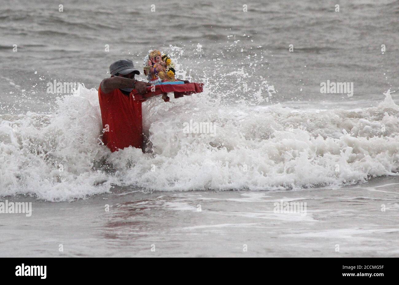 Ein Mann versucht, die Idole des Elefantenköpfigen Hindu-gottes Ganesh während des Festivals vor Wellen zu schützen.aufgrund der Coronavirus-Pandemie haben Freiwillige, die von der städtischen Behörde ernannt wurden, das Eintauchen von Ganpati-Idolen gemacht, damit das göttliche Bewusstsein weit und breit reicht, damit viele Menschen davon profitieren, Ein ritueller Teil des Ganesh Chaturthi Festivals. Stockfoto