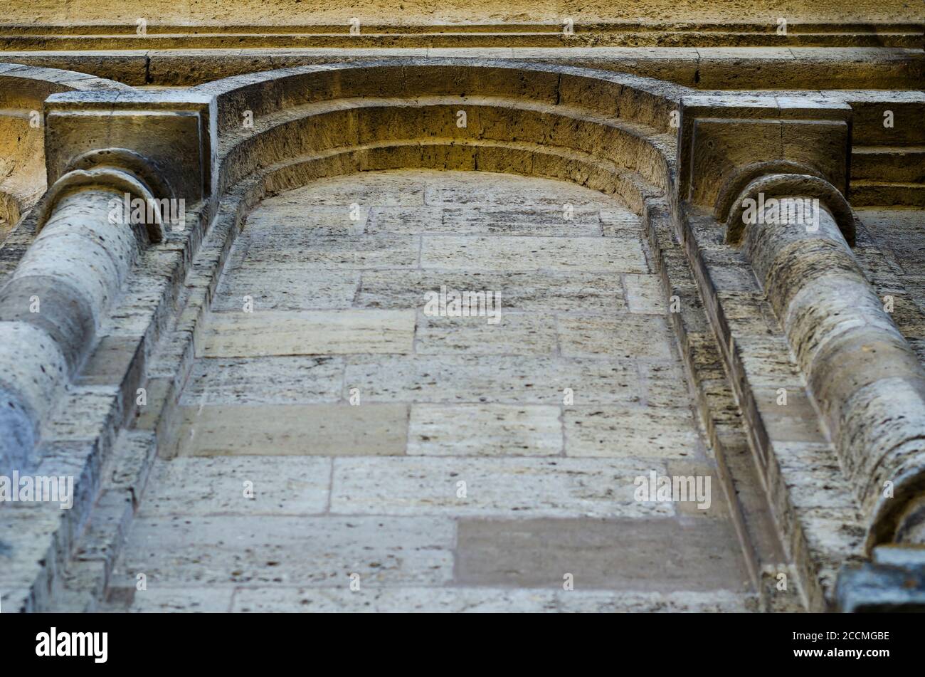 Fragment der Fassade eines alten Gebäudes aus Muschelstein. Außenwand mit zwei Säulen und einem Bogen in zurücktretender Perspektive. Tourismus und Reisen. Sho Stockfoto