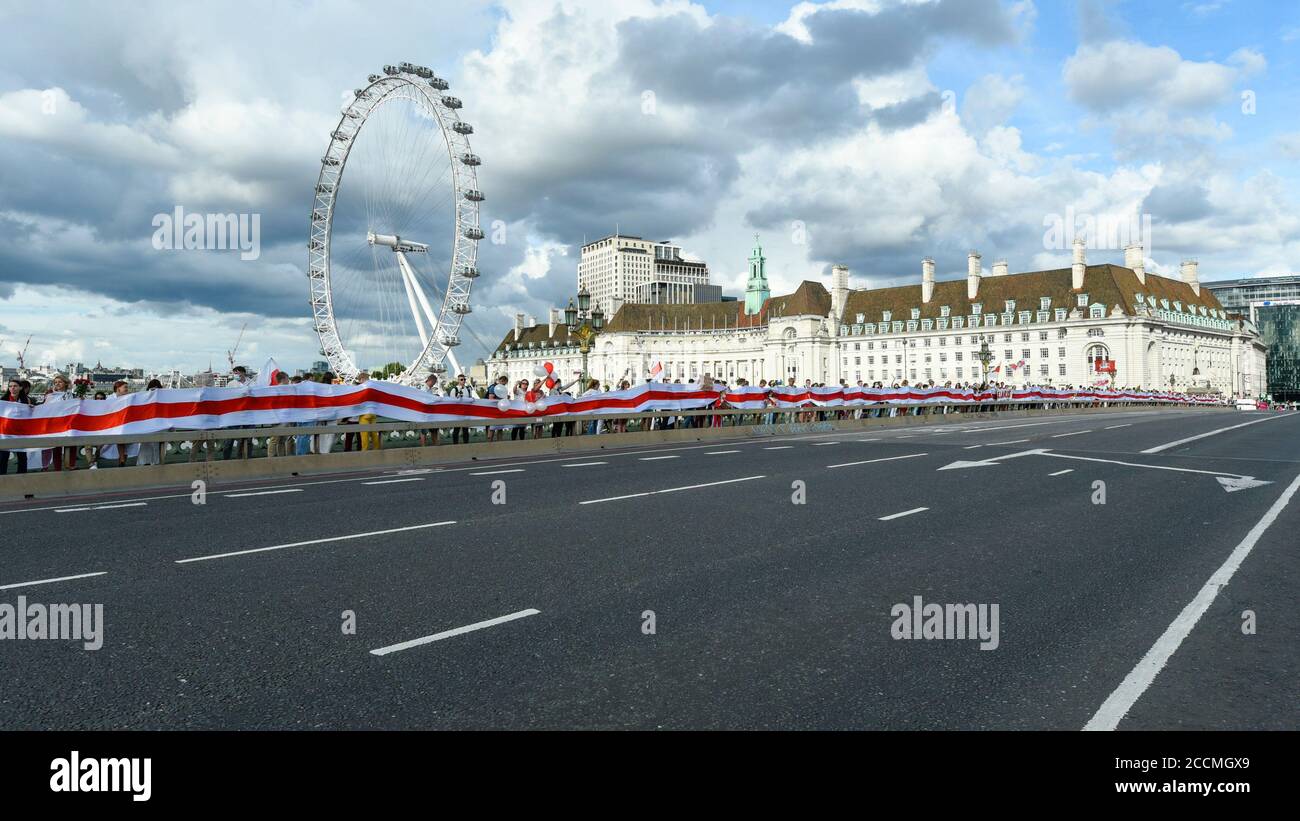 London, Großbritannien. 23. August 2020. Mitglieder der belarussischen Gemeinschaft der Hauptstadt versammeln sich, um eine Kette menschlicher Freiheit zu bilden, die eine riesige weißrussische Flagge auf der Westminster Bridge zeigt, in Solidarität mit den Menschen in Belarus, die gegen die Wiederwahl von Präsident Alexander Lukaschenko protestieren. Kredit: Stephen Chung / Alamy Live Nachrichten Stockfoto