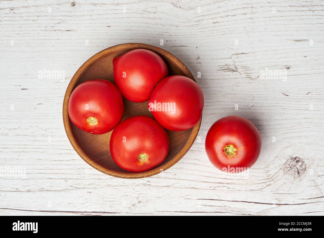 Draufsicht auf frische natürliche rohe Tomaten in Holzschüssel Auf hellem Holzhintergrund Stockfoto