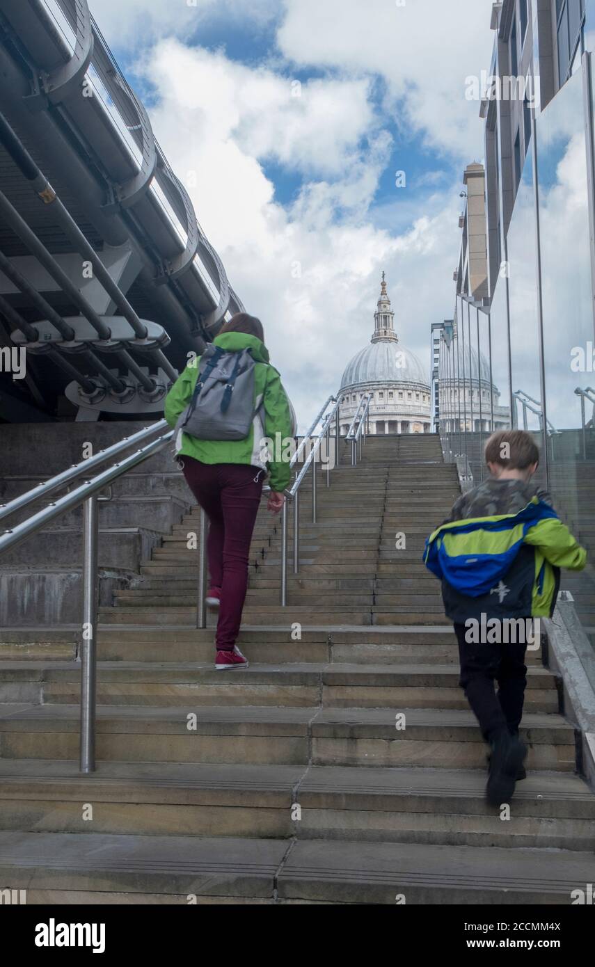 Mutter und Sohn gehen die Stufen hinauf an der Millennium Brücke Zur St Paul's Cathedral in London Stockfoto