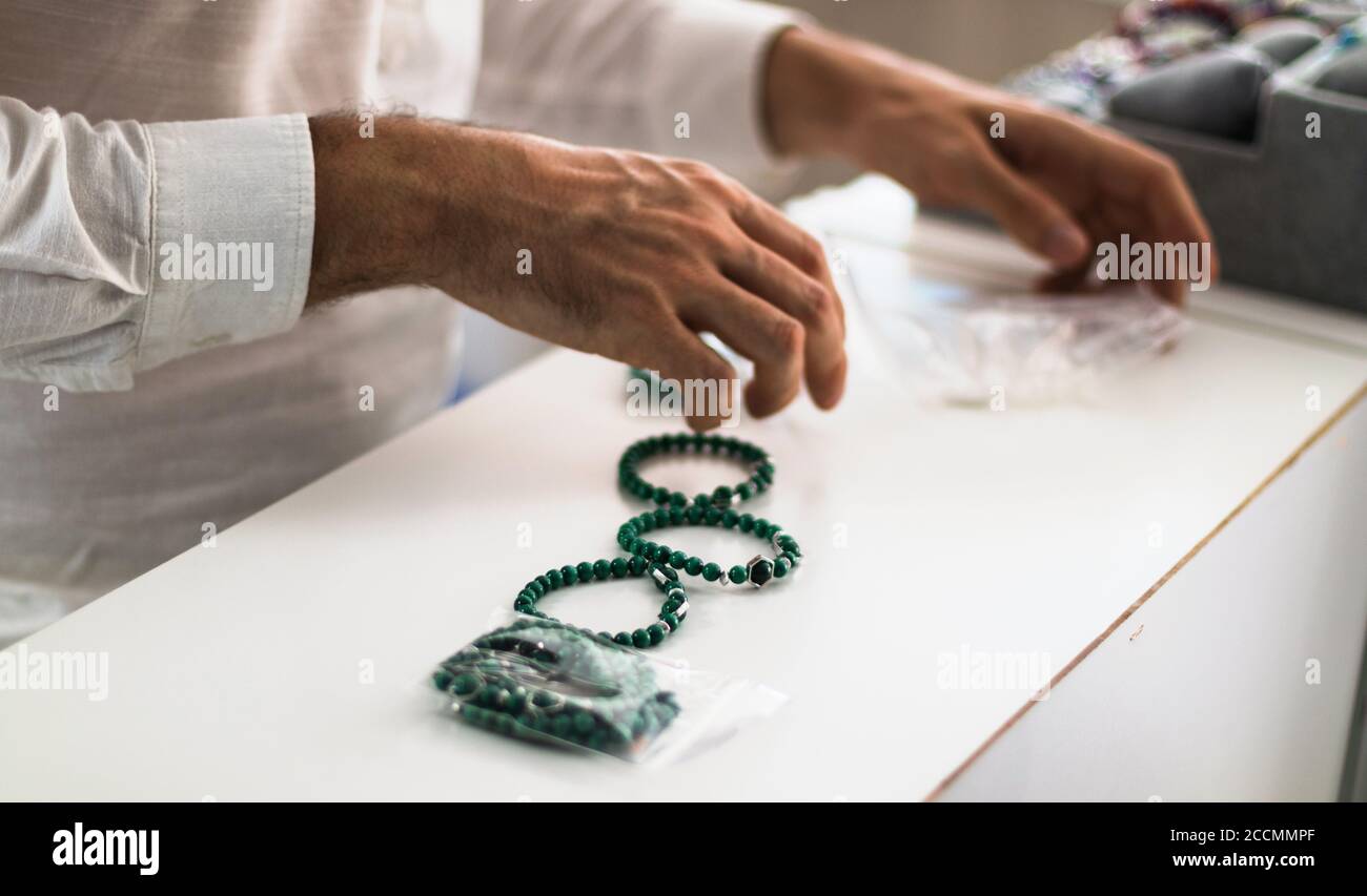 Juwelier Mann Hände arbeiten in seinem Geschäft Organisation verschiedener Arten von Armbändern. Stockfoto