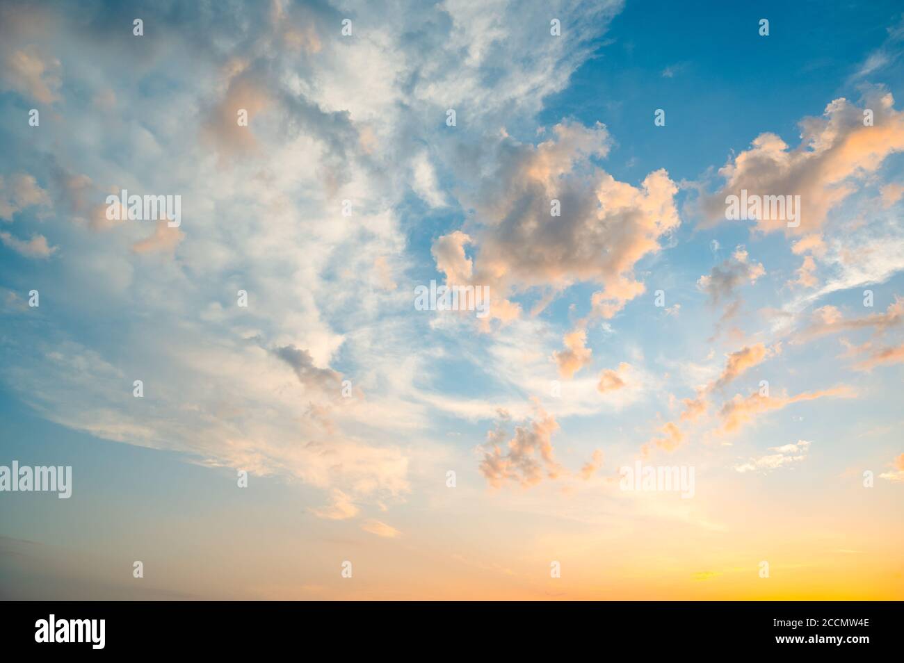 Schöner Sommerhimmel voller Wolken bei Sonnenuntergang zur goldenen Stunde. Interessante warme Farben am Horizont. Stockfoto