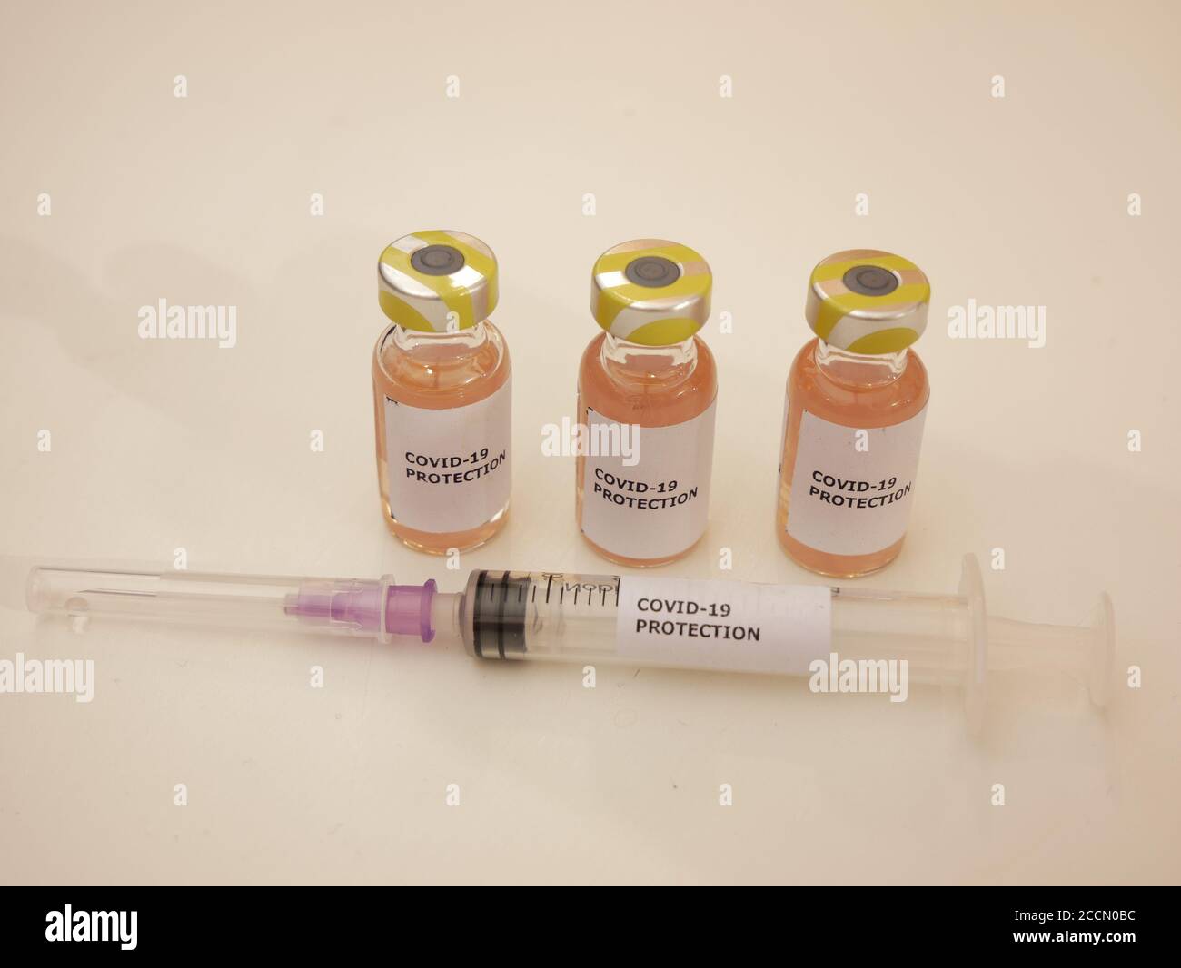 Impfstofffläschchen gegen Covid-19 mit Injektionsnadel und Schutz Gegen Coronavirus-Etikett mit hellem Hintergrund Stockfoto