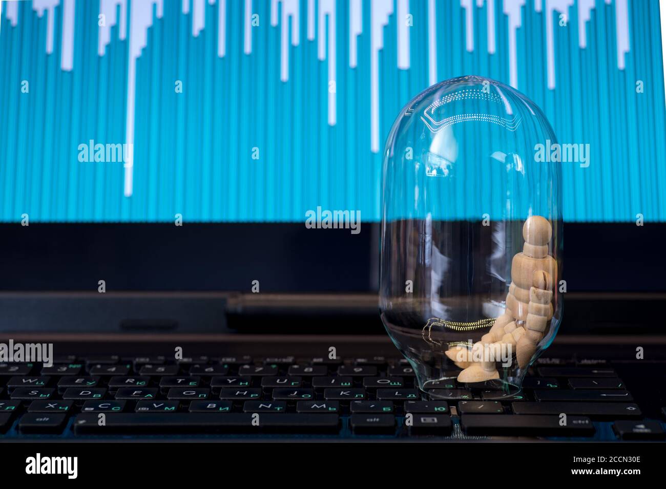 Holzmann in einer Glasflasche auf einer schwarzen Laptop-Tastatur auf dem Hintergrund eines Bildschirms mit einer Farbkarte. Stockfoto