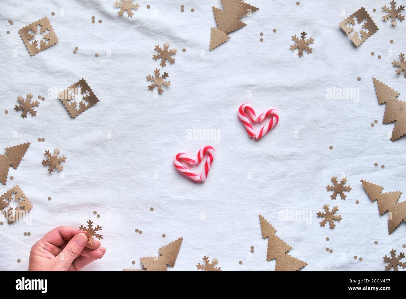 Weihnachten flach legen mit weiblichen Hand hält Schneeflocke Konfetti. Zero Waste umweltfreundliche Einrichtung aus Bastelpapier - Weihnachtsbaum Silhouetten, Schneeflocken in br Stockfoto