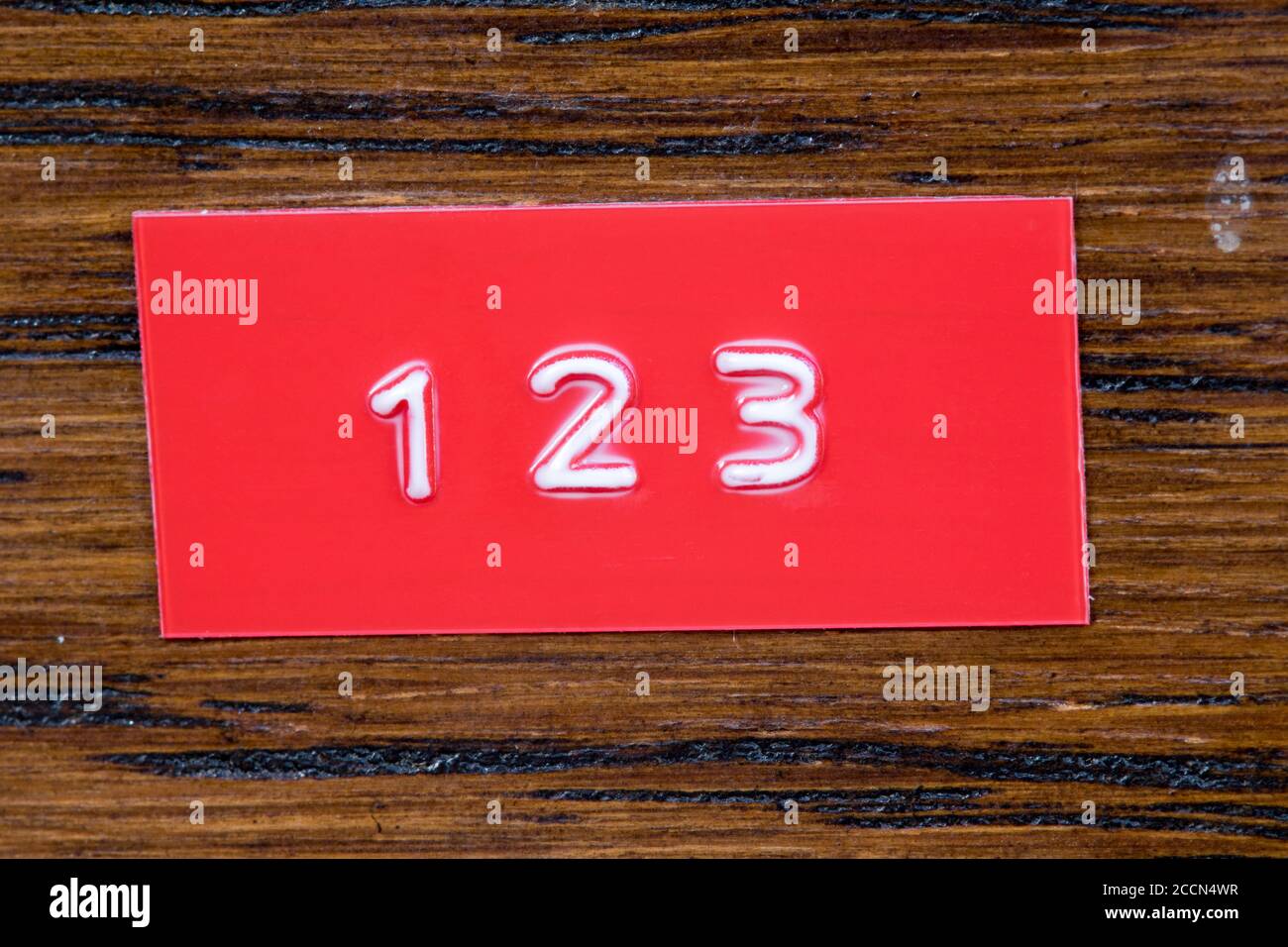 Prägeband mit den Ziffern 123 auf lackiertem Holz Hintergrund Stockfoto