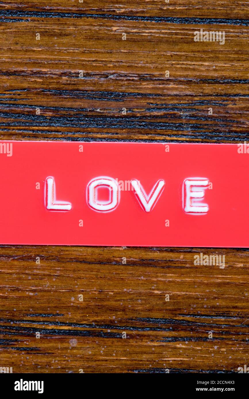 Geprägtes Band mit den Worten Liebe auf lackiertem Holz Hintergrund Stockfoto