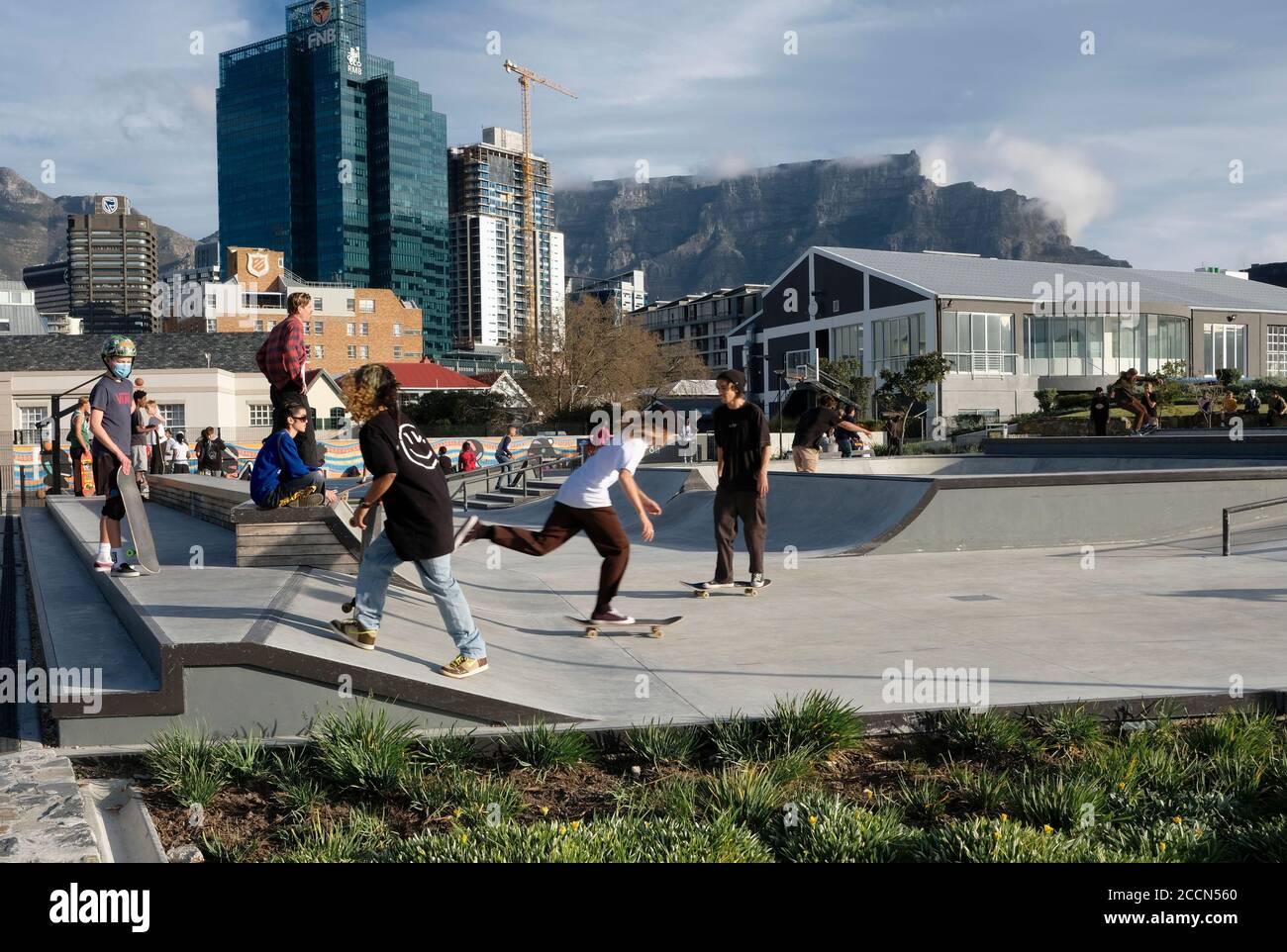 Skater auf ihren Skateboards im öffentlichen Skatepark im V&A Battery Park mit Tafelberg im Hintergrund in Kapstadt, Südafrika. Stockfoto