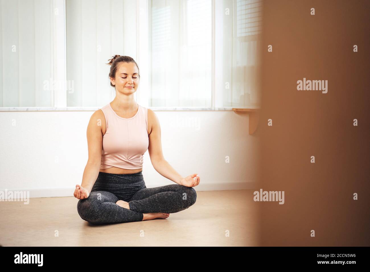 Volle Länge der kaukasischen jungen Frau praktiziert Yoga Lotusstellung In der Wohnung Stockfoto