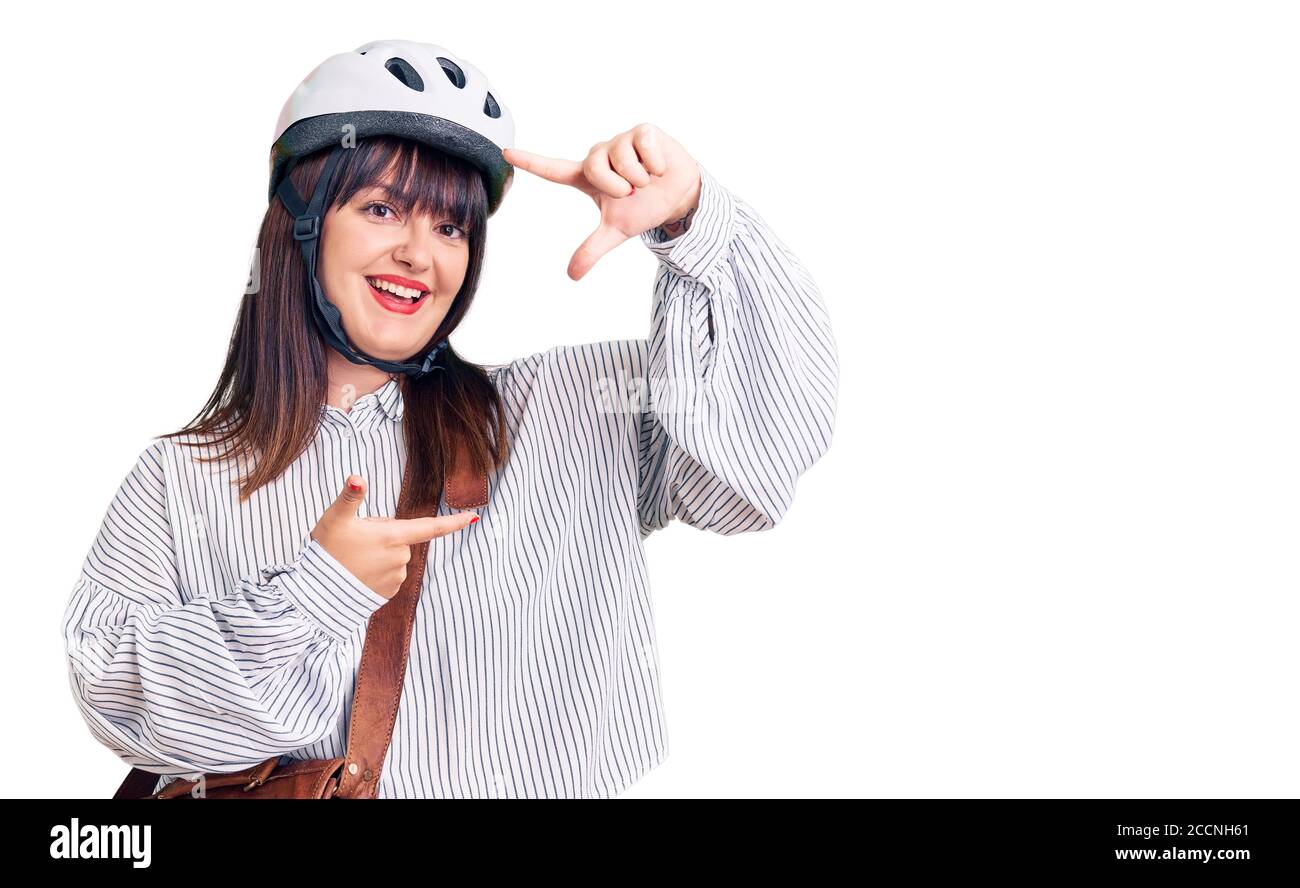 Junge plus size Frau trägt Fahrradhelm und Ledertasche lächelnd machen Rahmen mit Händen und Fingern mit glücklichen Gesicht. Kreativität und Fotografie konz Stockfoto