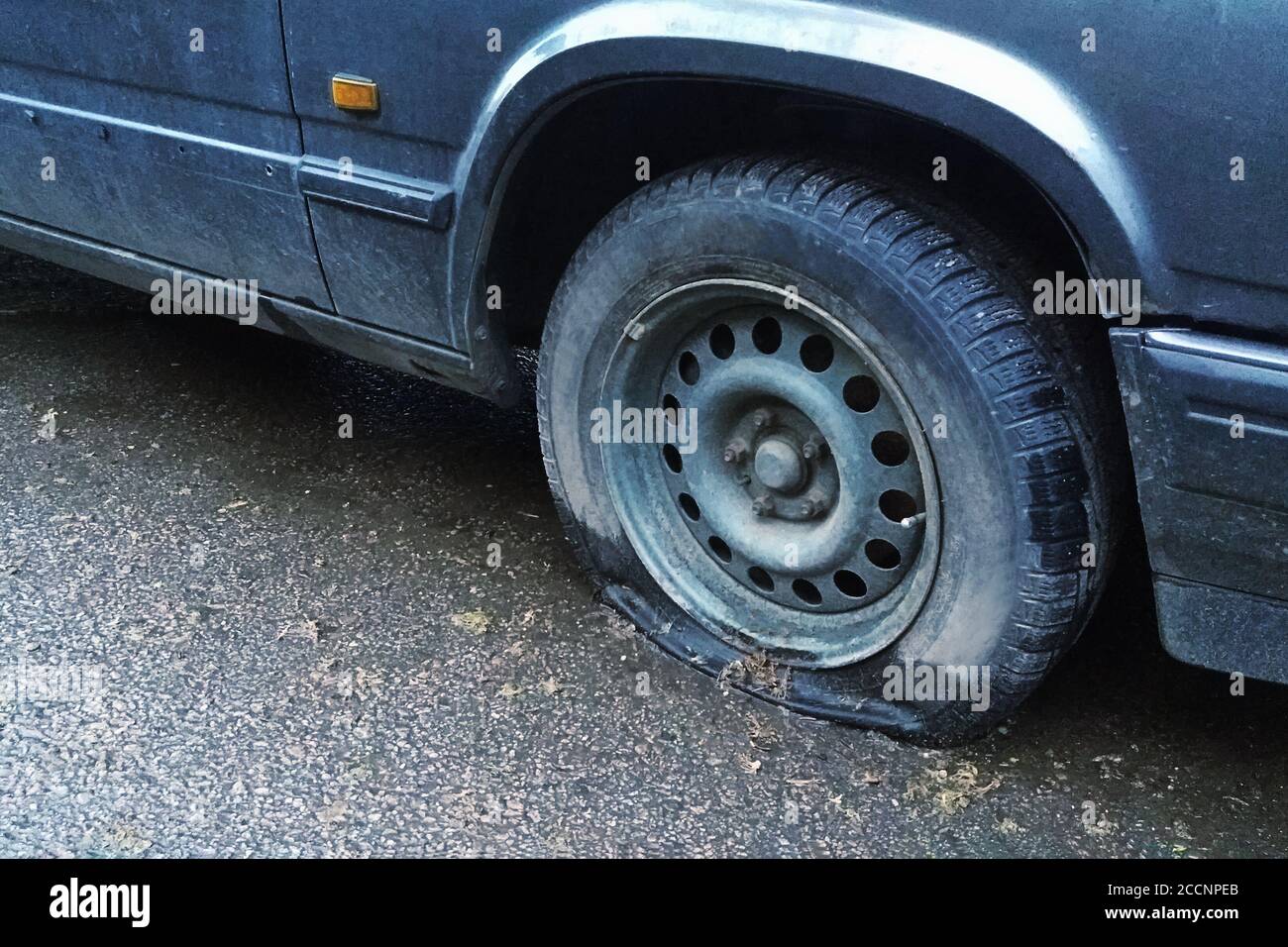 Altes Auto mit Reifenpanne auf der Straße, Nahaufnahme Stockfoto