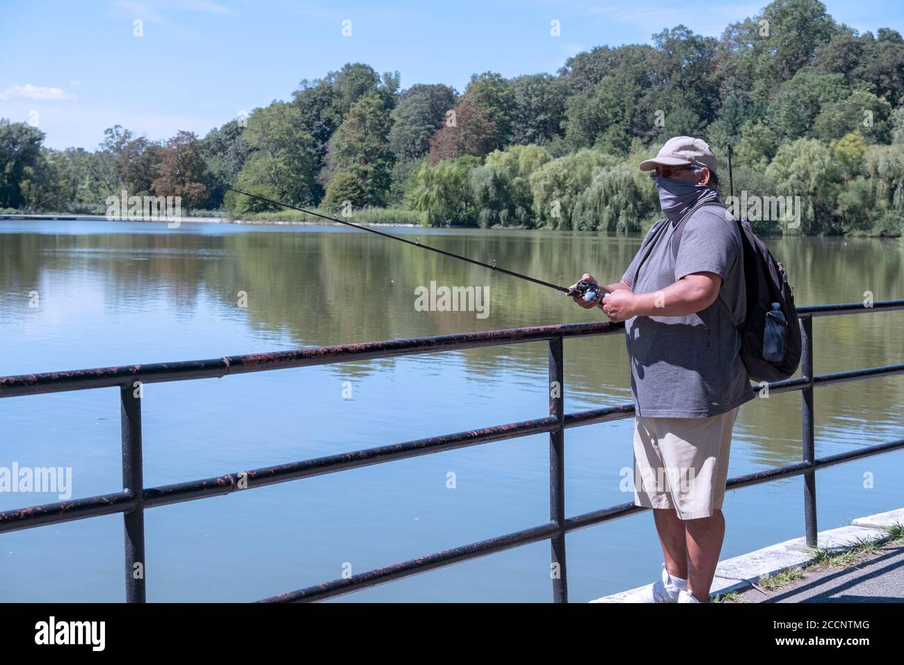Ein Mann mittleren Alters, der einen Halstuch trägt, fischt im See am Kissena Park in Flushing, Queens, New York City. Stockfoto