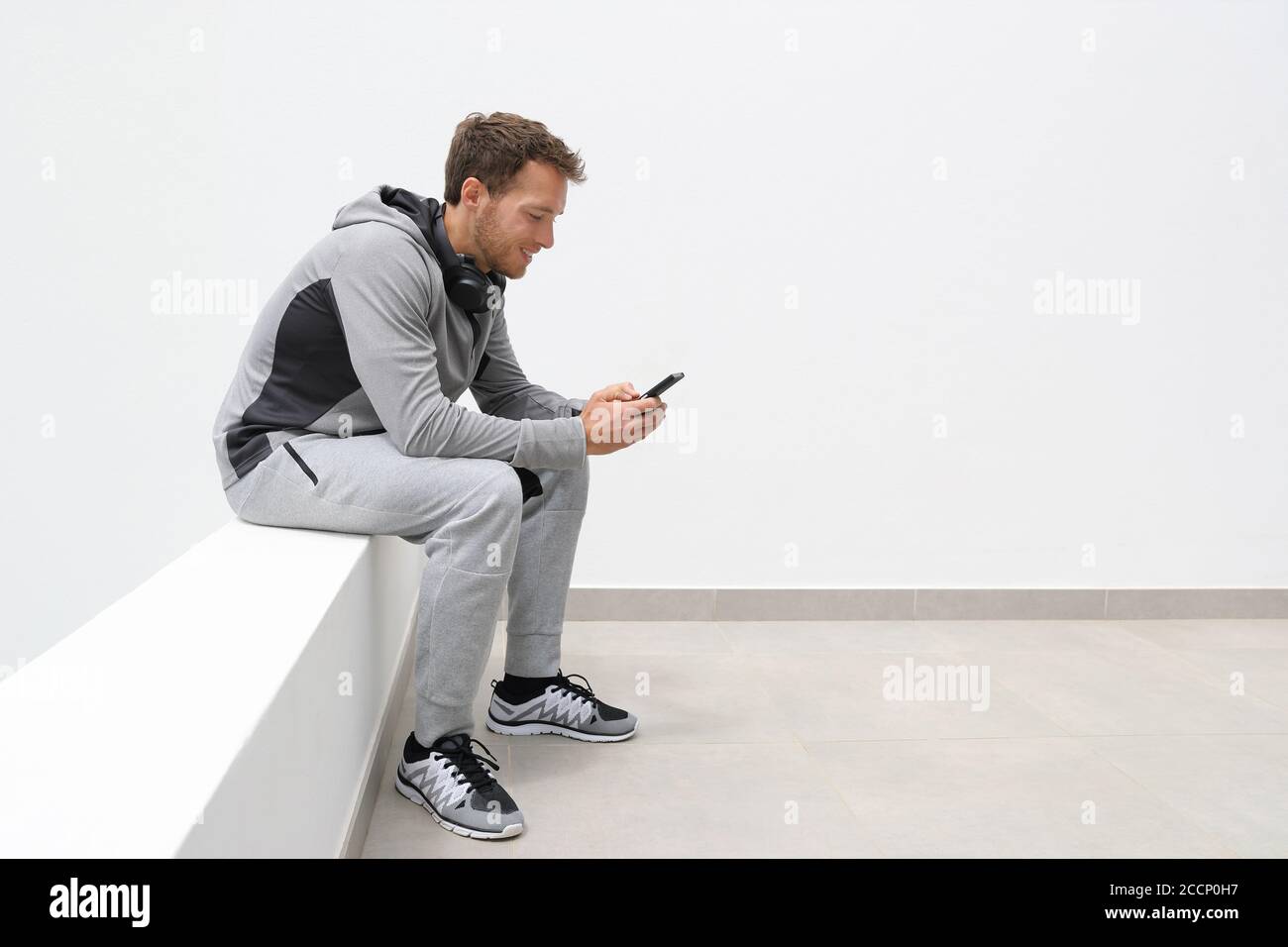 Aktiver Lebensstil junger Mensch hält Smartphone Online-Video ansehen oder SMS-Nachrichten SMS. Fitness-Mann mit Telefon-App auf Jogging Pause entspannen Stockfoto