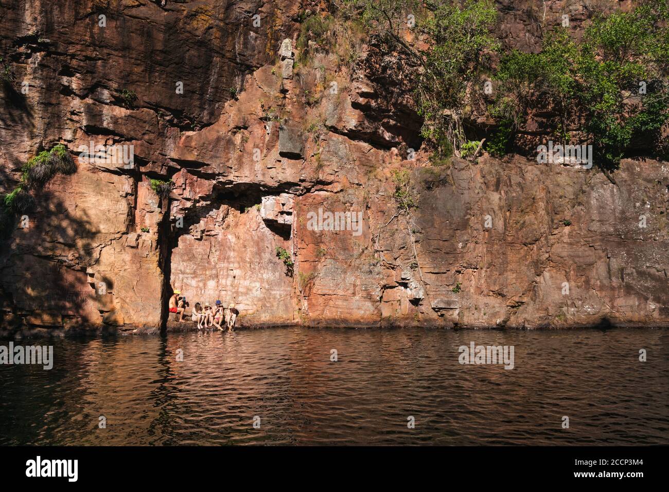 Gruppe junger Leute, die Spaß haben, schwimmen an einem Wasserloch. Vertikale Felswand. Nachmittag Sonnenuntergang, goldene Stunde. Florence Falls, Litchfield, Australien Stockfoto