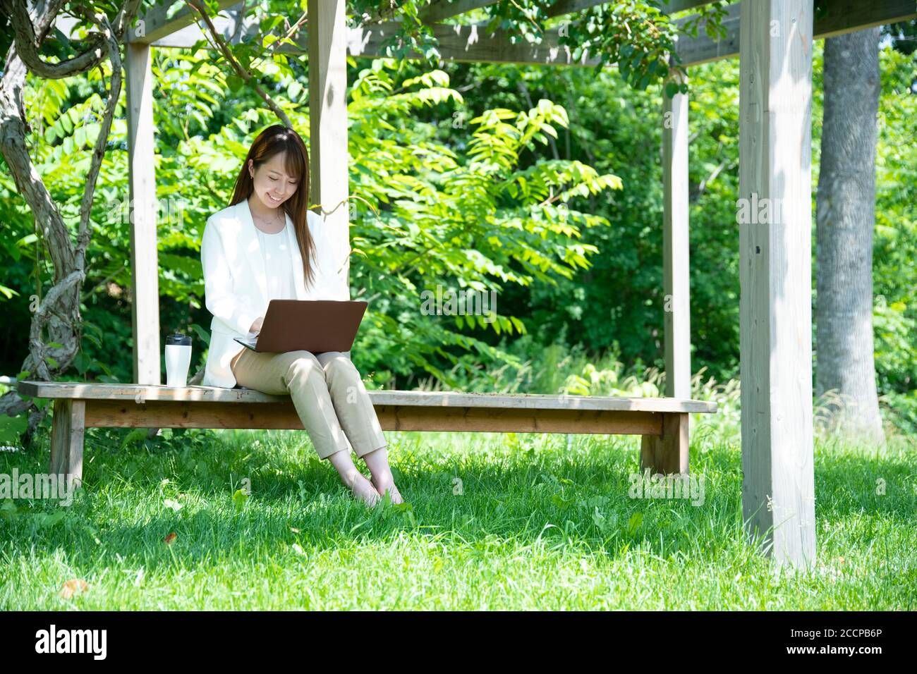 Junge Frau, die unter der Pergola arbeitet Stockfoto