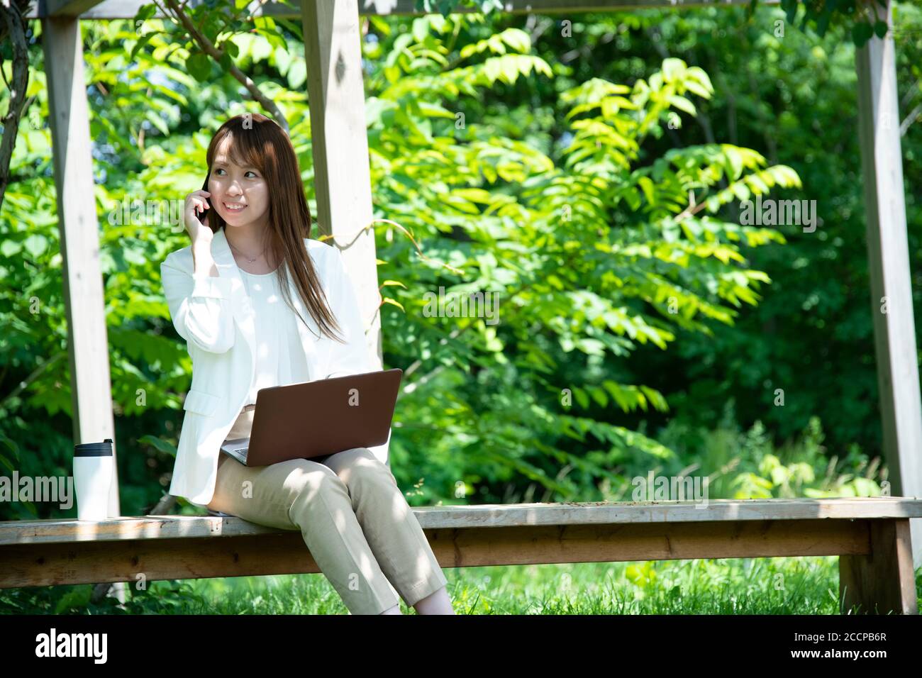 Junge Frau, die unter der Pergola arbeitet Stockfoto