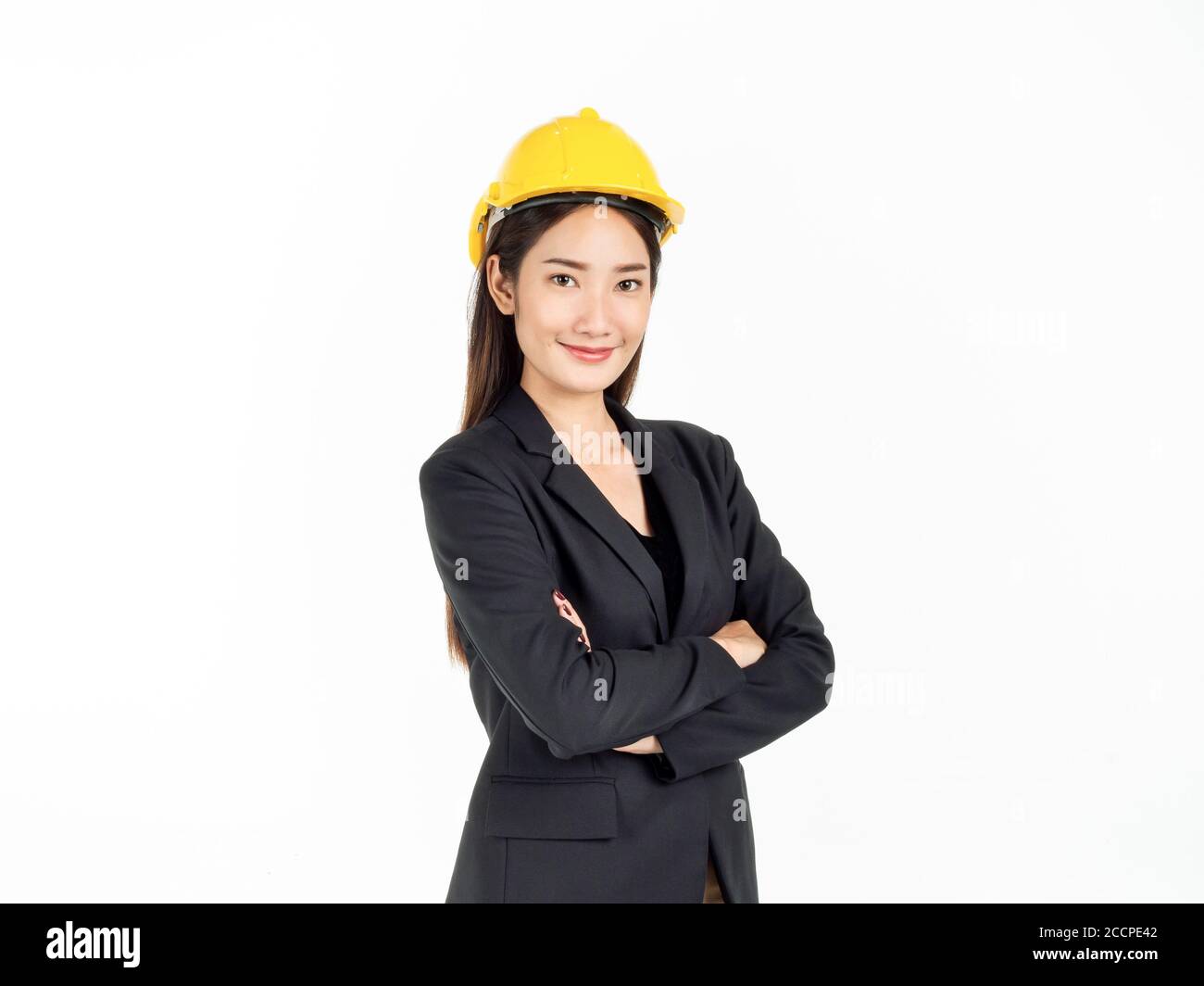 Junge asiatische Geschäftsfrau lächelnd trägt schwarzen Anzug und gelben Schutzhelm stehen mit ihren Armen gefaltet. Porträt einer Ingenieurin suchen confi Stockfoto
