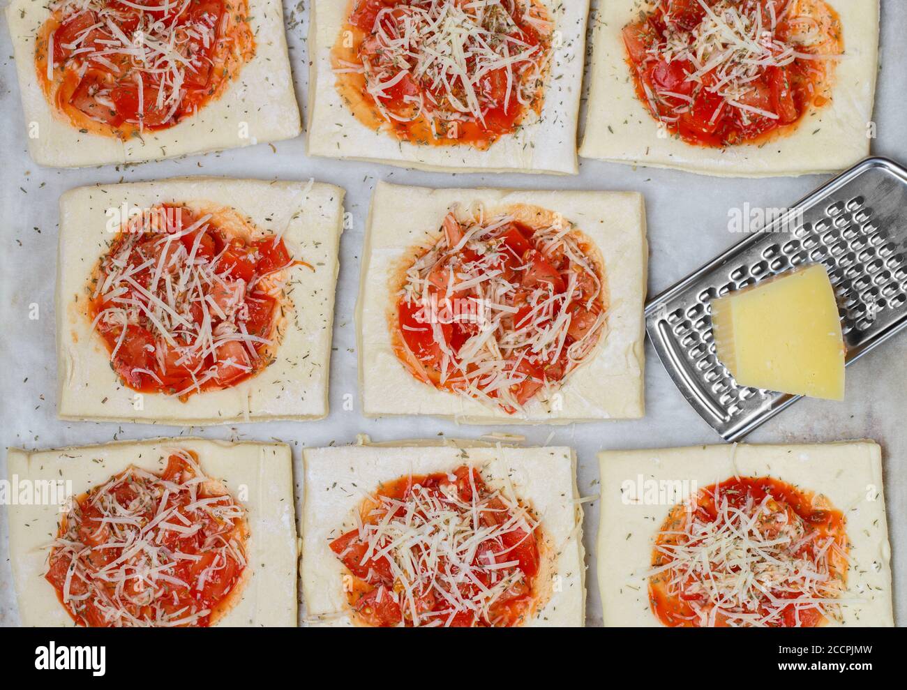 Kochen hausgemachte Kuchen aus Blätterteig mit Tomaten, Zwiebeln, Käse Mozzarella und Thymian. Mini-Pizza. Selektiver Fokus, Draufsicht Stockfoto